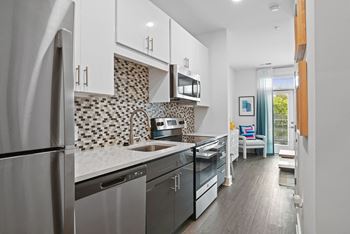 a kitchen with stainless steel appliances and white cabinets at Link Apartments® Mint Street, Charlotte, North Carolina